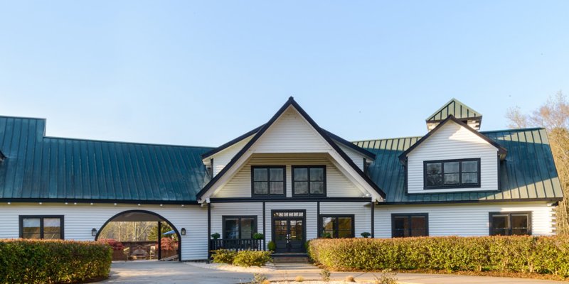 A charming, spacious building with a green roof and a large front entrance, surrounded by well-maintained hedges. A serene, welcoming environment.