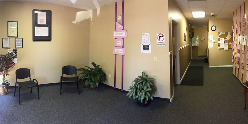 A warm, welcoming lobby with simple seating, plants, and motivational messages on the wall. The hallway leads to additional spaces with soft lighting.