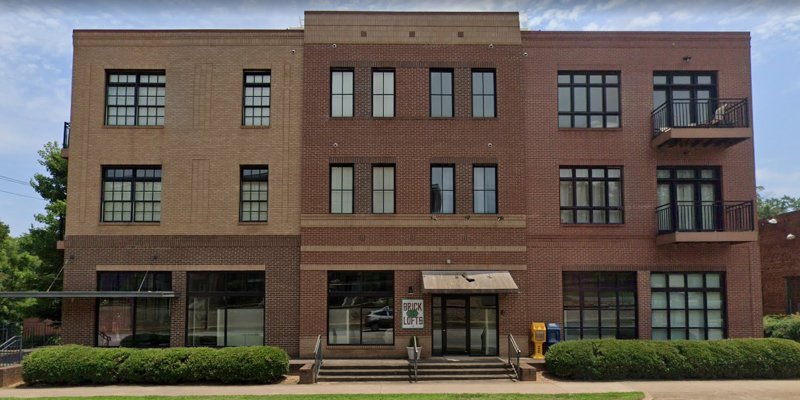  Charming brick building with large windows and balconies, offering a modern and inviting urban living space with well-maintained greenery.