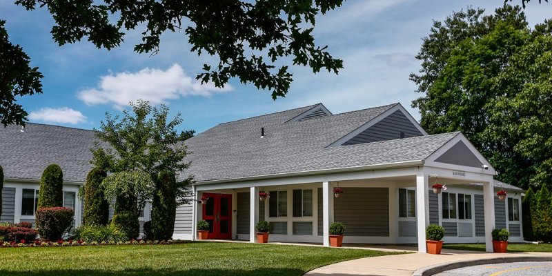 A charming building with a well-manicured lawn, bright red doors, and lush greenery. The peaceful surroundings offer a welcoming atmosphere.