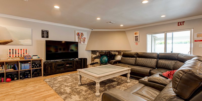  Cozy living room with plush leather seating, a large TV, and a fireplace, offering a comfortable space for relaxation and entertainment.