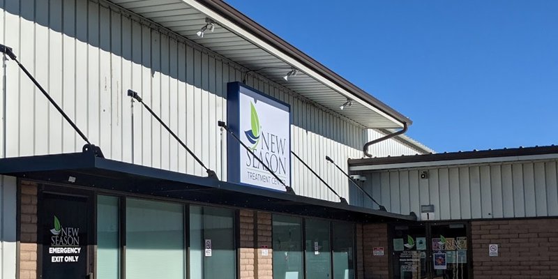  The exterior of the New Season Treatment Center, featuring a modern sign, a clean brick facade, and a bright, clear sky, creating an inviting atmosphere.