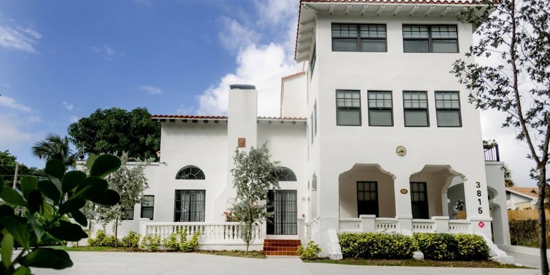 A beautiful, white Mediterranean-style building with a red-tiled roof and arched windows. Surrounded by greenery, it offers a peaceful atmosphere.