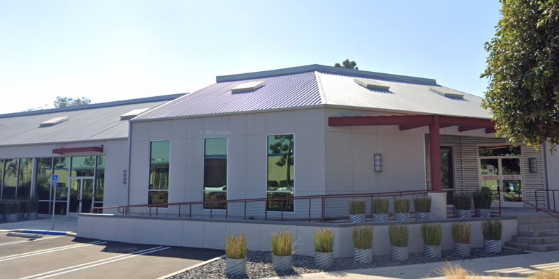  A modern building with a sleek metal roof, large windows, and accessible ramps, surrounded by greenery, creating a welcoming and professional atmosphere.