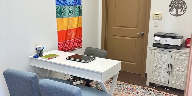 A small, inviting office with a colorful tapestry, cozy chairs, and a vibrant rug. The space offers a calm, welcoming atmosphere for meetings.