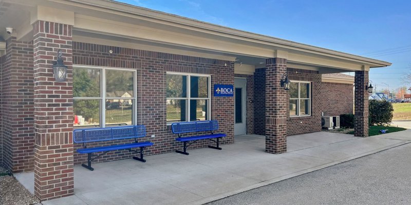  Charming brick entrance at Boca Recovery Center with blue benches and a welcoming sign, creating a warm and inviting atmosphere for visitors.