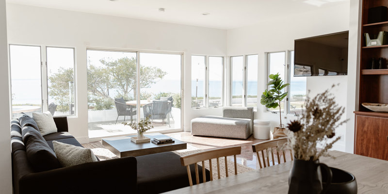 Bright, airy living room with modern decor, large windows offering stunning ocean views, and comfortable seating for relaxation.