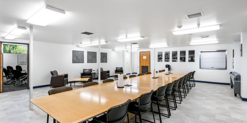 A spacious conference room with a long table, comfortable chairs, and bright lighting. Modern decor and clean lines create a professional atmosphere.