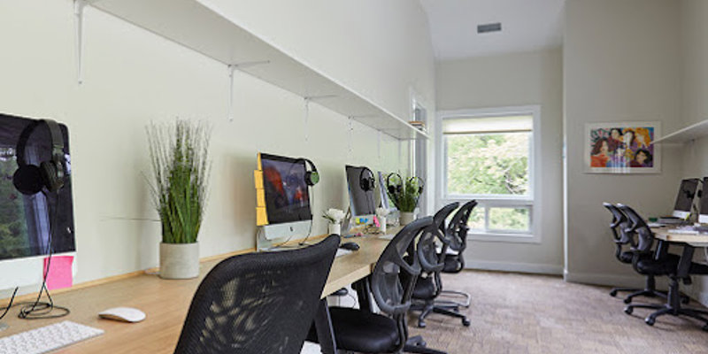 A bright, modern workspace with comfortable chairs, sleek desks, and computers, providing a productive and inviting environment for work or study.