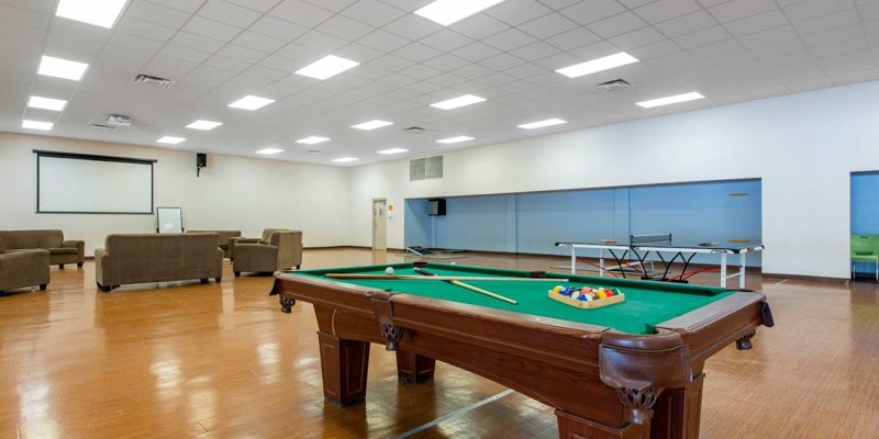  A spacious recreation room featuring a pool table, ping pong table, and comfortable seating, offering a relaxing and social environment.