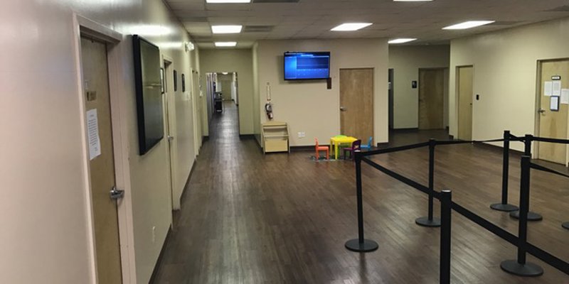 A clean, spacious hallway with wooden flooring, ample lighting, and a small play area for children, creating a welcoming environment.