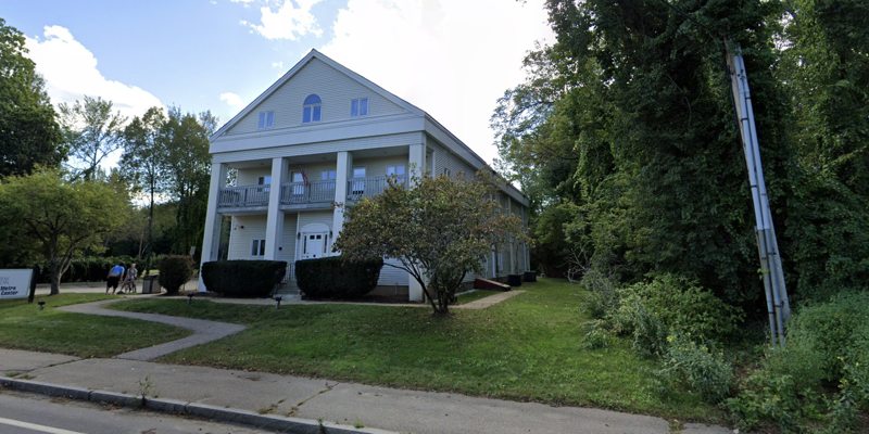 A grand, colonial-style building with large columns and a welcoming front entrance, surrounded by lush greenery, housing the Concord Metro Treatment Center.