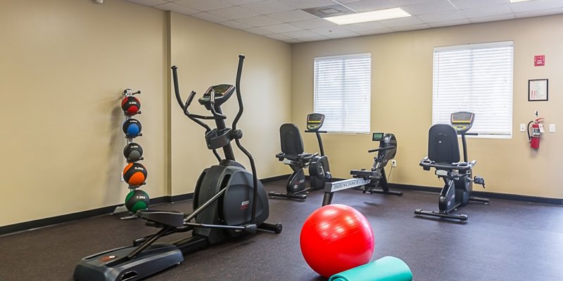  A well-equipped fitness room with exercise machines, colorful medicine balls, and a yoga mat, providing a space for a healthy and active lifestyle.