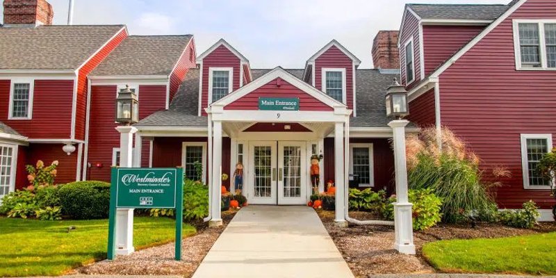 A welcoming entrance to a recovery center with a classic red exterior, charming decor, and well-maintained landscaping, creating an inviting atmosphere.