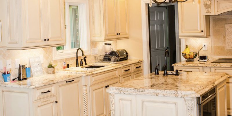 Elegant kitchen with cream-colored cabinets, granite countertops, a central island, and a decorative chandelier, offering a warm and inviting space.