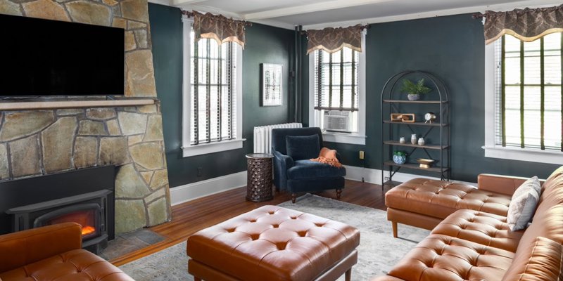 A cozy and inviting lounge with a stone fireplace, comfortable leather seating, and warm decor. Large windows allow natural light to brighten the space, creating a relaxing atmosphere ideal for unwinding or group activities.