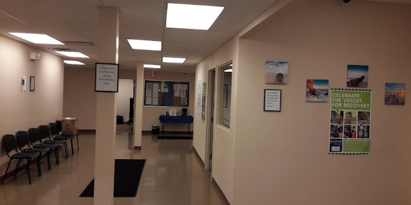  A clean, well-lit hallway with motivational posters, neatly arranged chairs, and comfortable waiting areas, creating a welcoming and supportive atmosphere.