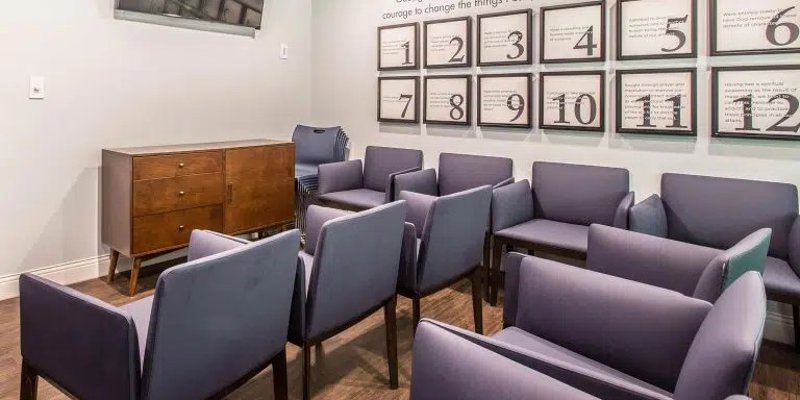 Cozy meeting room with comfortable chairs arranged for group sessions, inspirational wall art, and a TV, providing a supportive and focused environment.