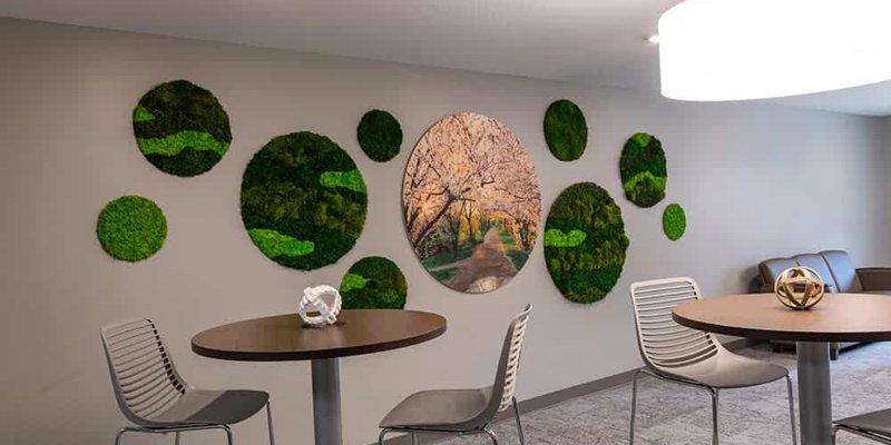 A modern lounge with stylish high-top tables, sleek chairs, and nature-inspired wall art, creating a calming and peaceful environment.