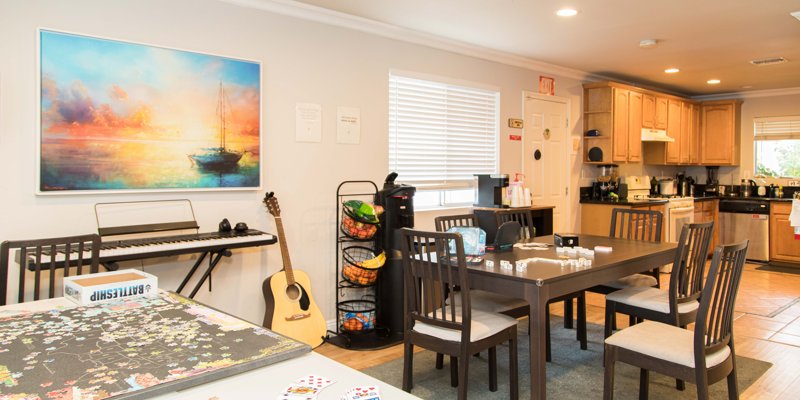  Bright and welcoming kitchen and dining area featuring a puzzle in progress, musical instruments, and a colorful painting on the wall.