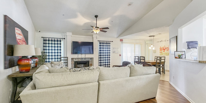 Spacious, inviting living room with soft, neutral-toned furniture, a ceiling fan, and a cozy fireplace, perfect for relaxation and socializing.