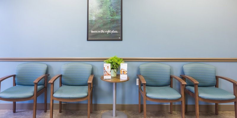 A welcoming waiting area with comfortable blue chairs, a small table with brochures, and a calming wall poster, creating a serene atmosphere.