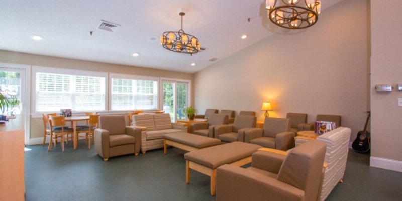 A cozy lounge area with comfortable seating, warm lighting, and large windows, perfect for relaxation and socializing in a welcoming environment.