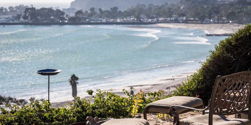 Scenic beachfront seating with cushioned chairs and a fire pit, offering breathtaking coastal views perfect for peaceful relaxation.