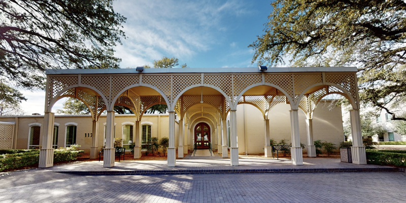 Grand entrance with intricate lattice arches, framed by majestic oak trees and a paved pathway, creating a welcoming and elegant setting.