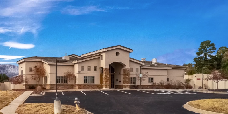 A modern treatment center with a spacious parking lot, stone accents, and scenic mountain views in the background, offering a peaceful and professional setting.