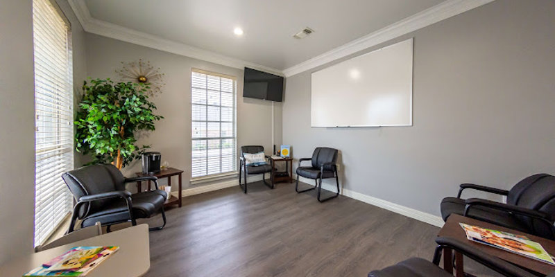 A bright, organized meeting room with comfortable chairs, a whiteboard, and a large window letting in natural light, fostering a peaceful environment.