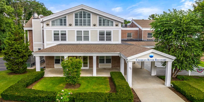 A welcoming recovery center with a classic, well-maintained exterior, surrounded by lush greenery, offering a peaceful and supportive environment.