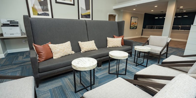 A modern and cozy seating area featuring a high-back sofa, plush pillows, and sleek round tables, perfect for relaxation and conversation.